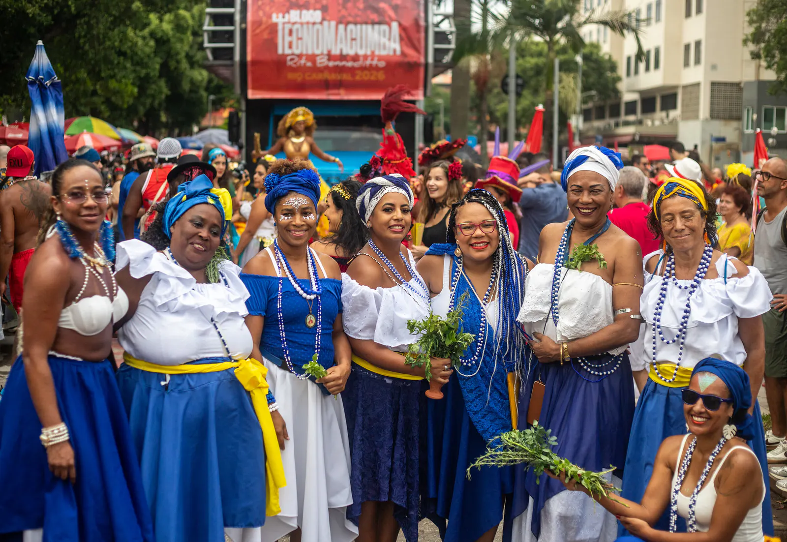 Gruppe von Menschen mit blauen und weißen Kleidern, Perlen und Blättern in ihren Händen, in Straßenparade.