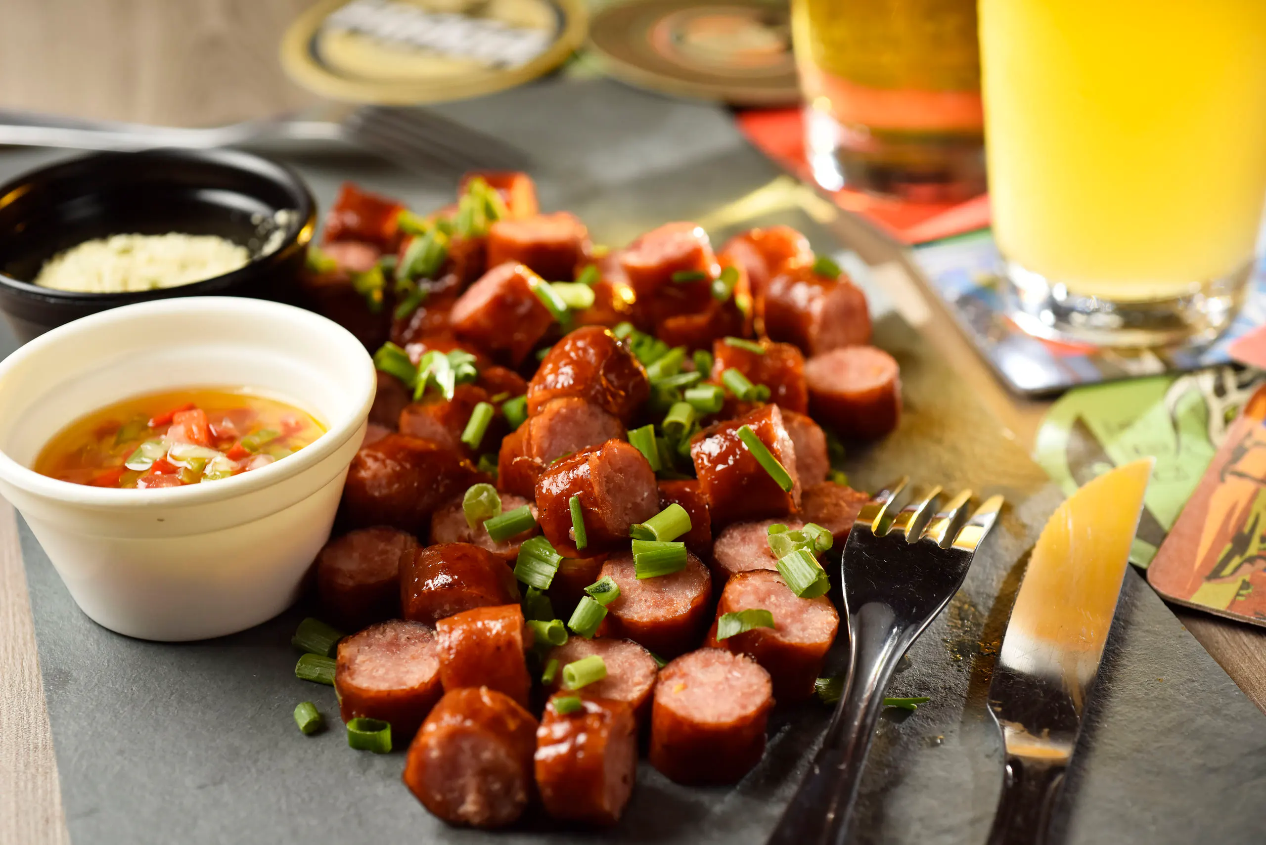 Handgemachte Wurst in Scheiben mit Soße und Schnittlauch, serviert neben Tassen Kaffee in einer Chopperia