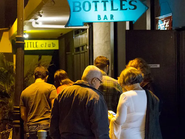 Gruppe von Personen in der Nacht am Eingang einer Bar, unter dem Bottles Bar Board