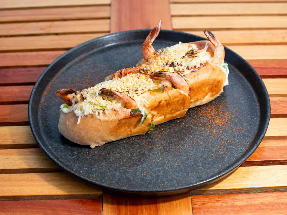 Mit Knoblauchcreme, Quadratgarnelen, Knoblauchporo, geriebenem Käse und Panko Pharofa gefülltes Crocant-Baguete. Eine Kombination