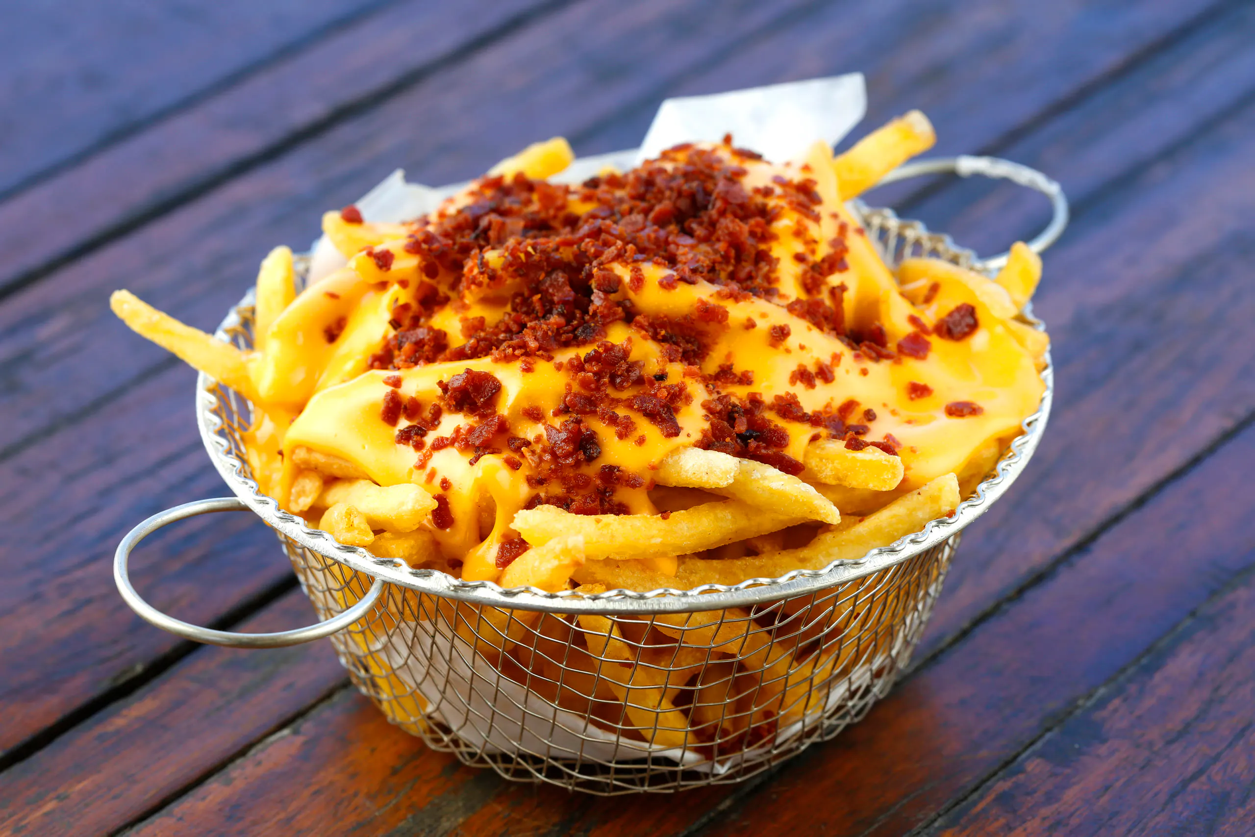 Batata Frita con Cheddar e Bacon: Porzione di patatine ricoperte di pancetta cremosa e friabile.