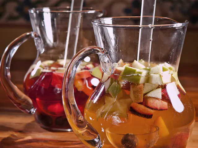 Deux cruches de verre avec saignement, une de vin rouge et une avec du vin léger et des morceaux de fruits, sur une table en bois.